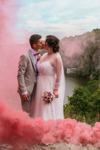 Man and woman standing against pink wall