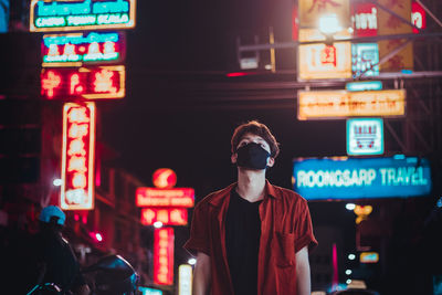 Full length of man standing on illuminated city at night