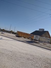 Road amidst buildings against clear blue sky