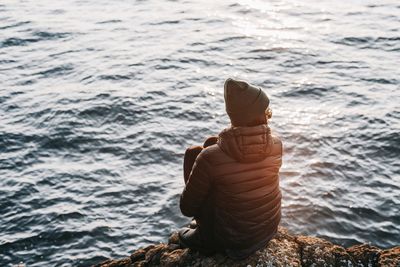 Man sitting on rock in sea