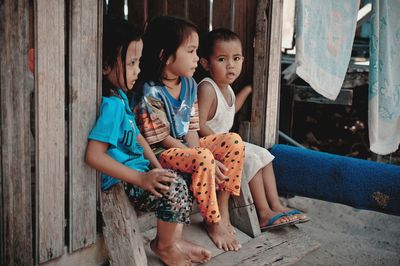 Full length of siblings sitting at doorway