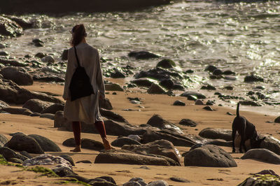 Rear view of man standing on rock at beach