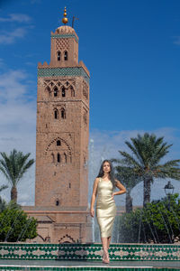 Full length of woman standing by building against sky