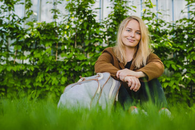 Portrait of smiling young woman with blond hair sitting on grass