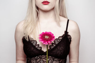 Young woman holding flower against white background