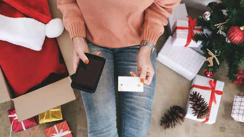 Midsection of woman holding credit card while using phone