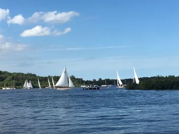 Sailboats sailing on sea against sky