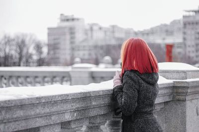 Rear view of woman standing on snow covered city in winter