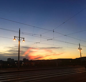 Silhouette of railroad tracks against sunset sky