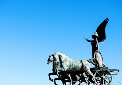 Low angle view of horse statue against clear blue sky