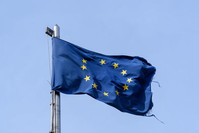 Low angle view of flag against clear blue sky