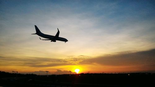 Low angle view of silhouette airplane against sky during sunset
