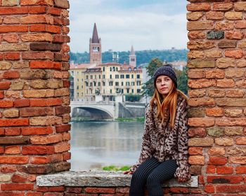 Portrait of young woman standing against brick wall