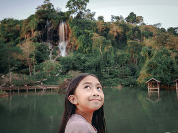 Portrait of woman by lake against trees