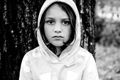 Portrait of girl in hood clothing against tree