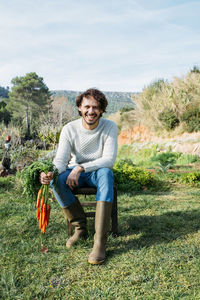 Farmer sitting on a chair, holding a bunch of carrots