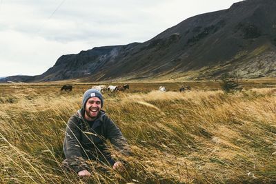 Portrait of smiling man standing on mountain against sky