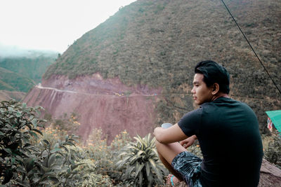 Side view of young man looking at mountains