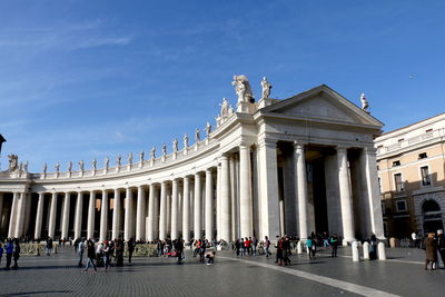 People on street against historical building during sunny day