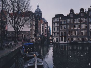 Boats in canal amidst city against sky