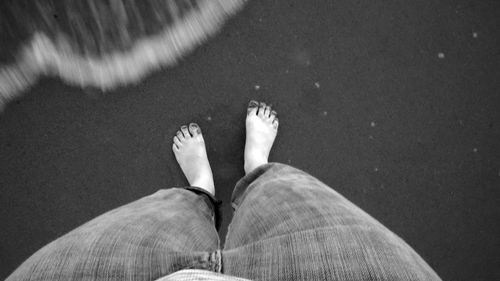 Low section of woman standing at sea shore