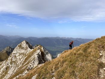 Rear view of man walking on mountain against sky