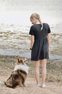 Full length of a young woman and dog on beach