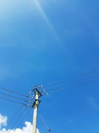 Low angle view of electricity pylon against blue sky