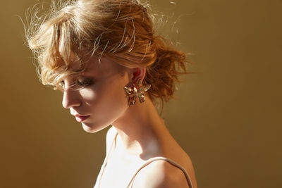Close-up of thoughtful bride with blond hair against brown background