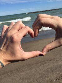 Midsection of hands on sea shore