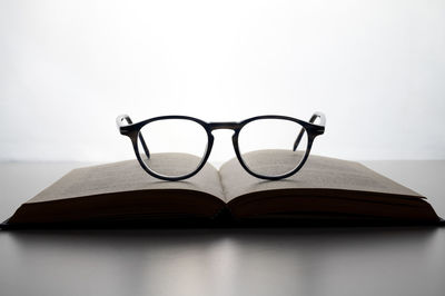 Open book, backlit, with glasses on it. viewing, reading, studying.