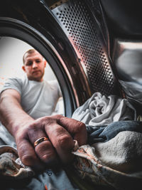 Low angle view of man putting garments in washing machine