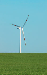 Wind turbines on field against clear sky