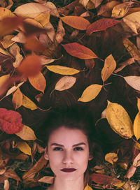 Close-up portrait of young woman with autumn leaves