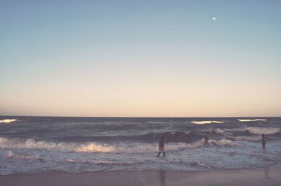 Silhouette man standing on beach against clear sky during sunset