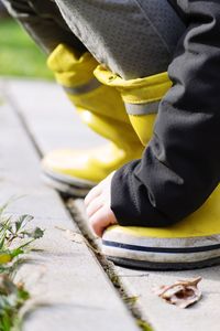 Low section of child wearing rubber boots on footpath