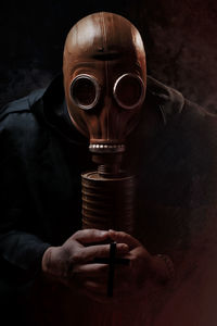 Man wearing gas mask against black background