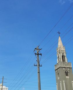 Low angle view of electricity pylon against blue sky