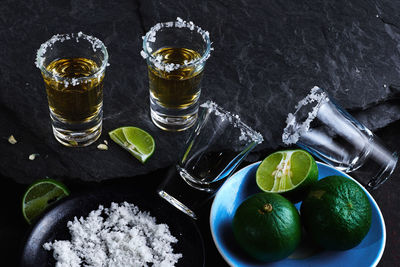 High angle view of tequila shots by lime and salt on table