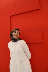 Portrait of young woman standing against yellow wall