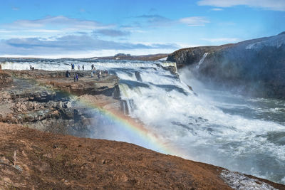 Tourists enjoying view of gullfoss waterfall in golden circle against blue sky