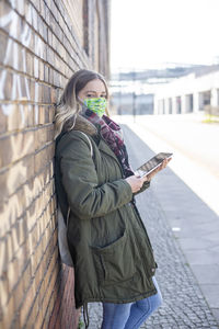 Full length of woman standing on mobile phone in city