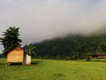 House on field by trees against sky