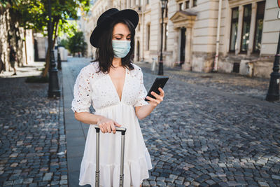 Young woman using phone while standing on street