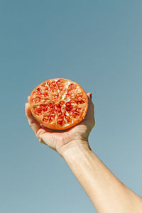 Close-up of hand holding apple against blue background