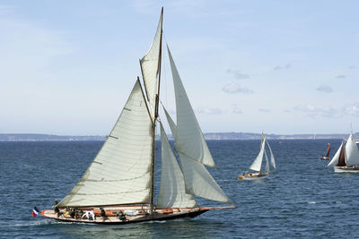 Boats in sea against cloudy sky