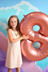 Portrait of girl holding number 8 inflatable ring against mural