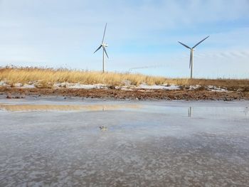 Wind turbines on land against sky