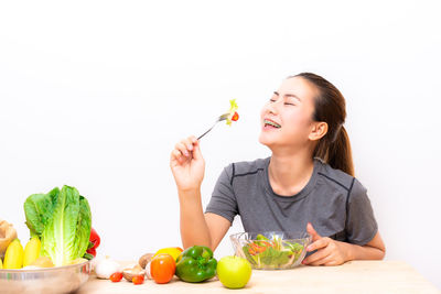 Young woman holding fruits against white background