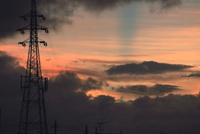 Low angle view of silhouette electricity pylon against sky during sunset